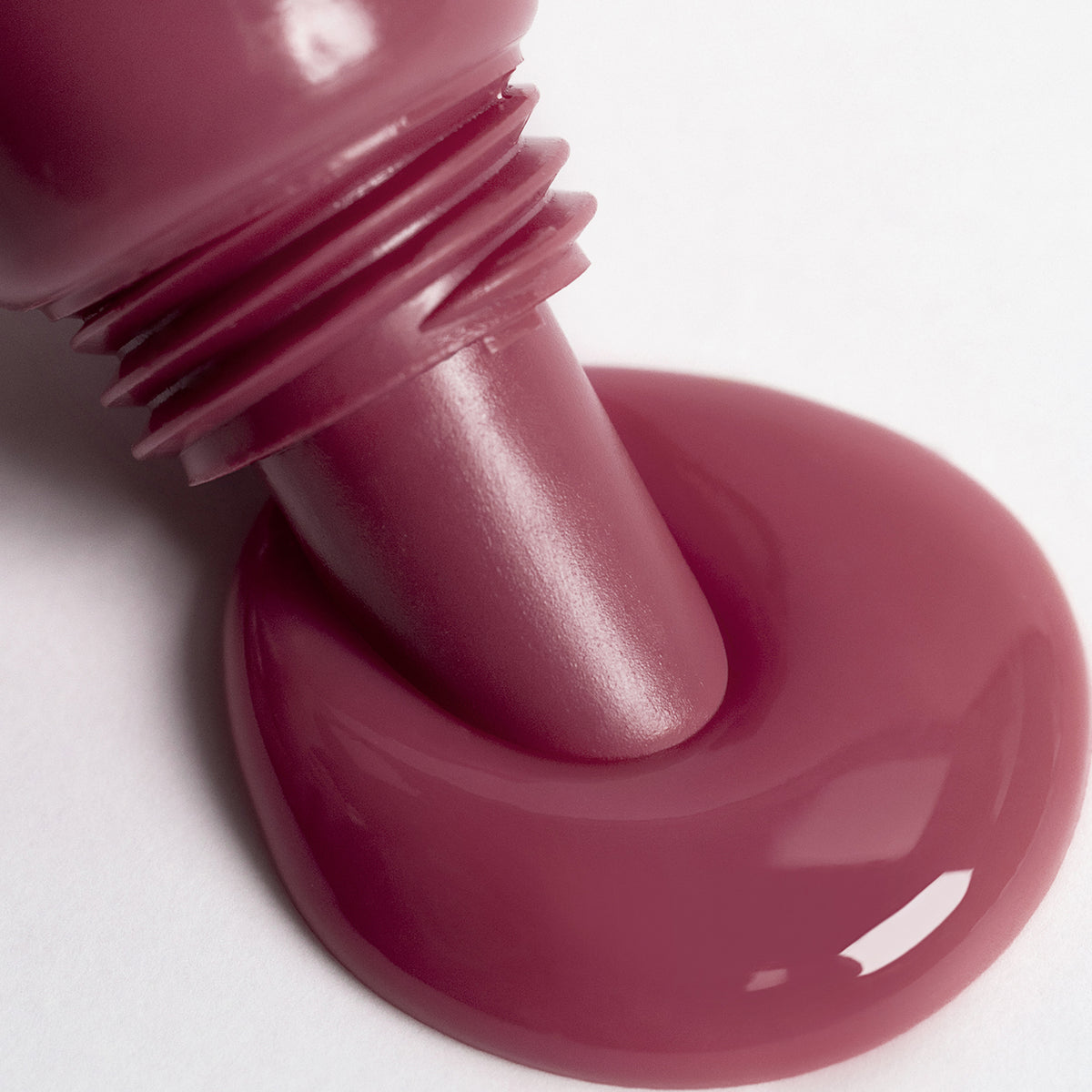 Nahaufnahme Lip Glow Oil Balm Raspberry, aus dem Applikator tritt die Textur auf eine weiße Oberfläche