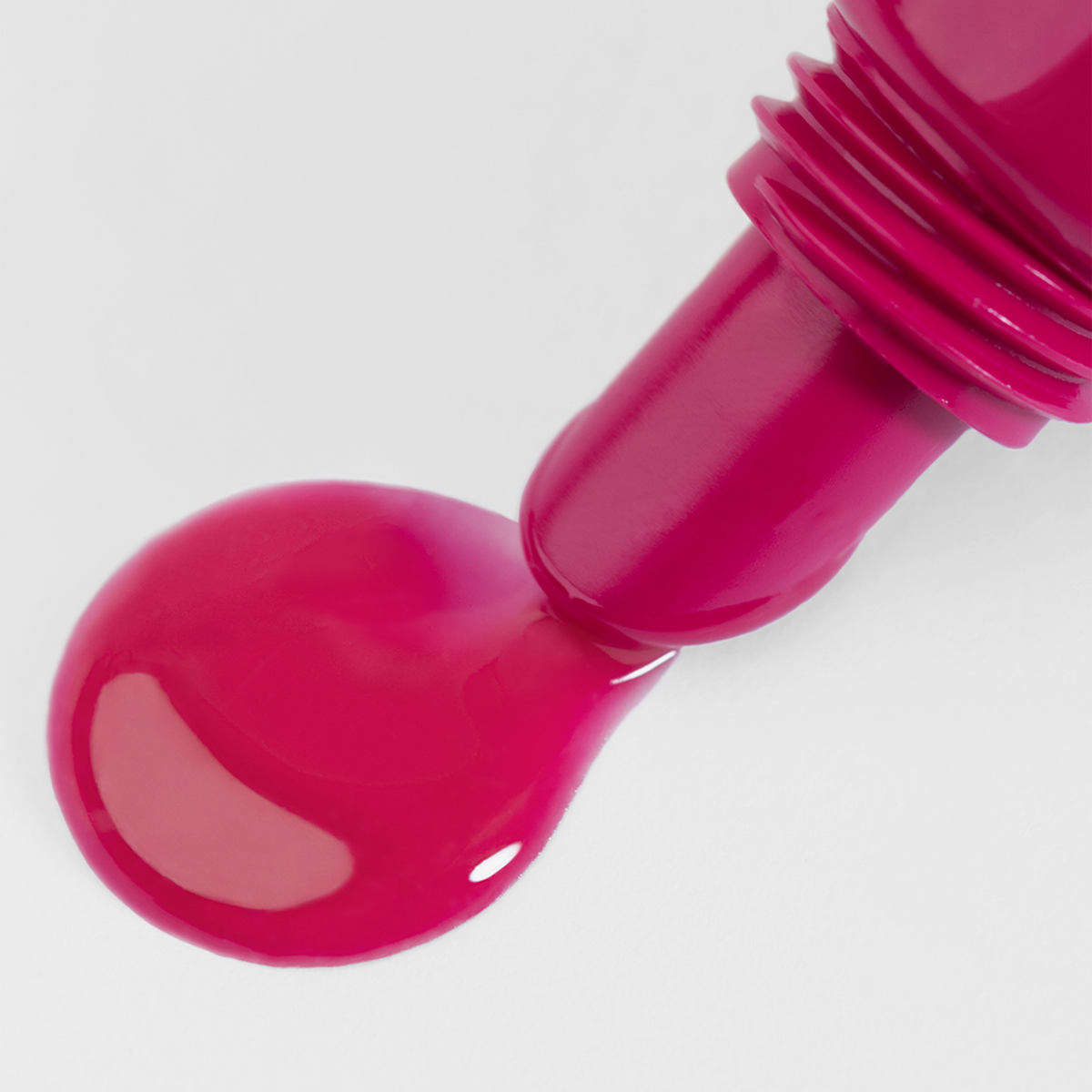 Der Lumene Lip Glow Oil Balm SPF30 in 3 Cherry tropft aus einer offenen Tube und bringt leuchtend rosa Farbe auf eine weiße Oberfläche.