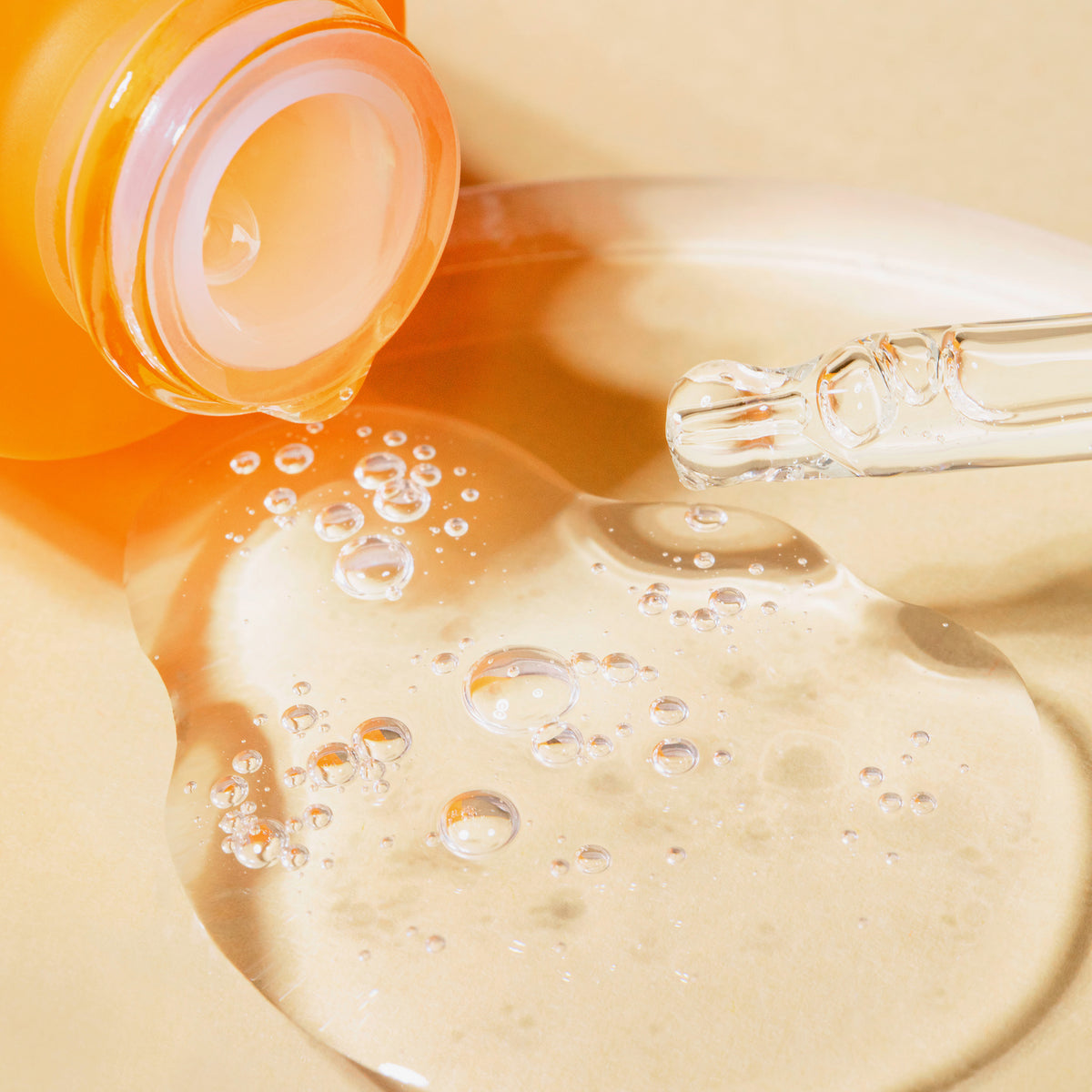 Nahaufnahme der offenen Flasche NORDIC-C [VALO] Glow Boost Essence von Lumene; klares Serum mit Bläschen fließt aus der orangefarbenen Flasche mit Glastropfer.