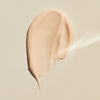 Ein beiger Cremestreifen von Lumene NORDIC-C [VALO] Glow Moisturizer auf einem hellen, glatten Untergrund.