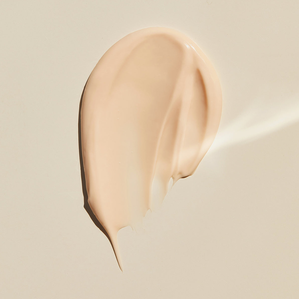 Ein beiger Cremestreifen von Lumene NORDIC-C [VALO] Glow Moisturizer auf einem hellen, glatten Untergrund.