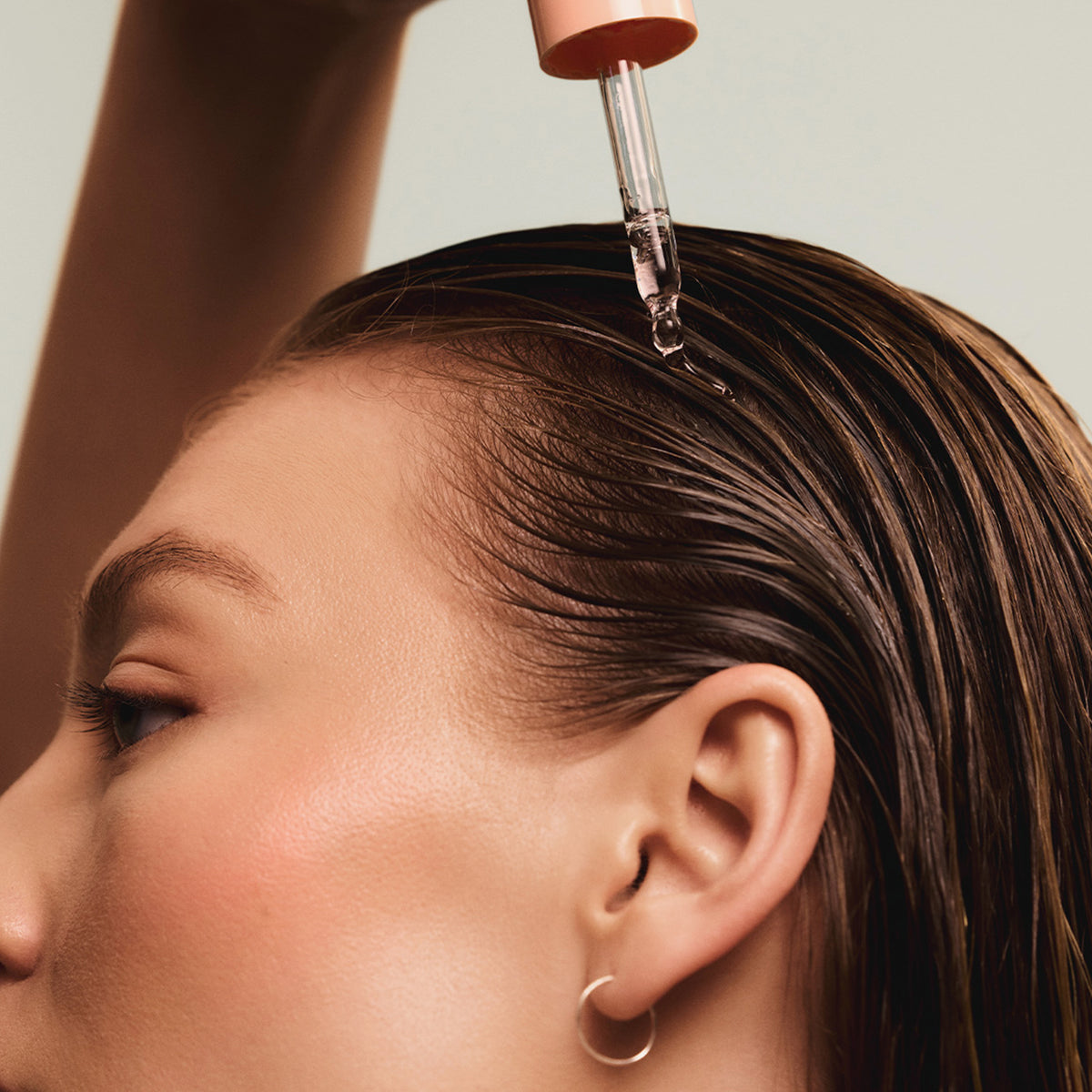 Eine Person trägt das maria nila Head & Hair Heal Soothing Serum mit einer Pipette auf ihre Kopfhaut auf.