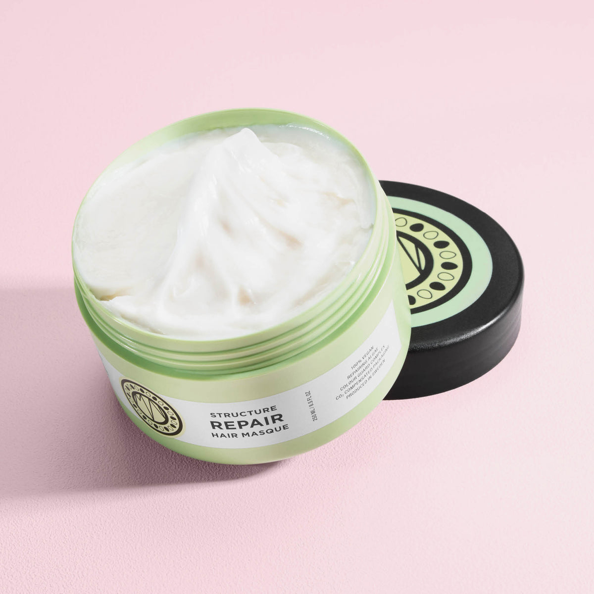 Geöffneter Tiegel von maria nila Structure Repair Masque mit cremig weißem Produkt auf hellrosa Hintergrund.
