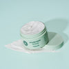 Offener mintgrüner maria nila Styling Paste Tiegel mit Paste auf einer passenden mintgrünen Oberfläche.