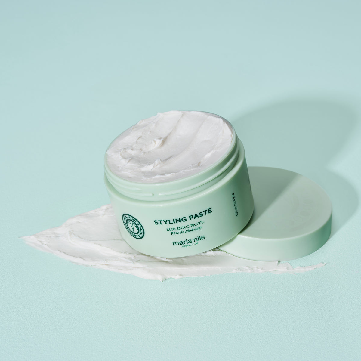 Offener mintgrüner maria nila Styling Paste Tiegel mit Paste auf einer passenden mintgrünen Oberfläche.