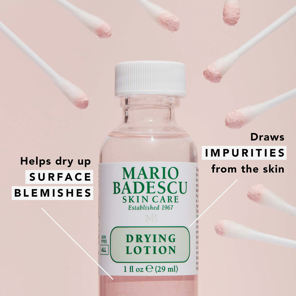 Flasche Mario Badescu Drying Lotion mit rosafarbener Lösung, umgeben von Wattestäbchen mit rosa Spitze.