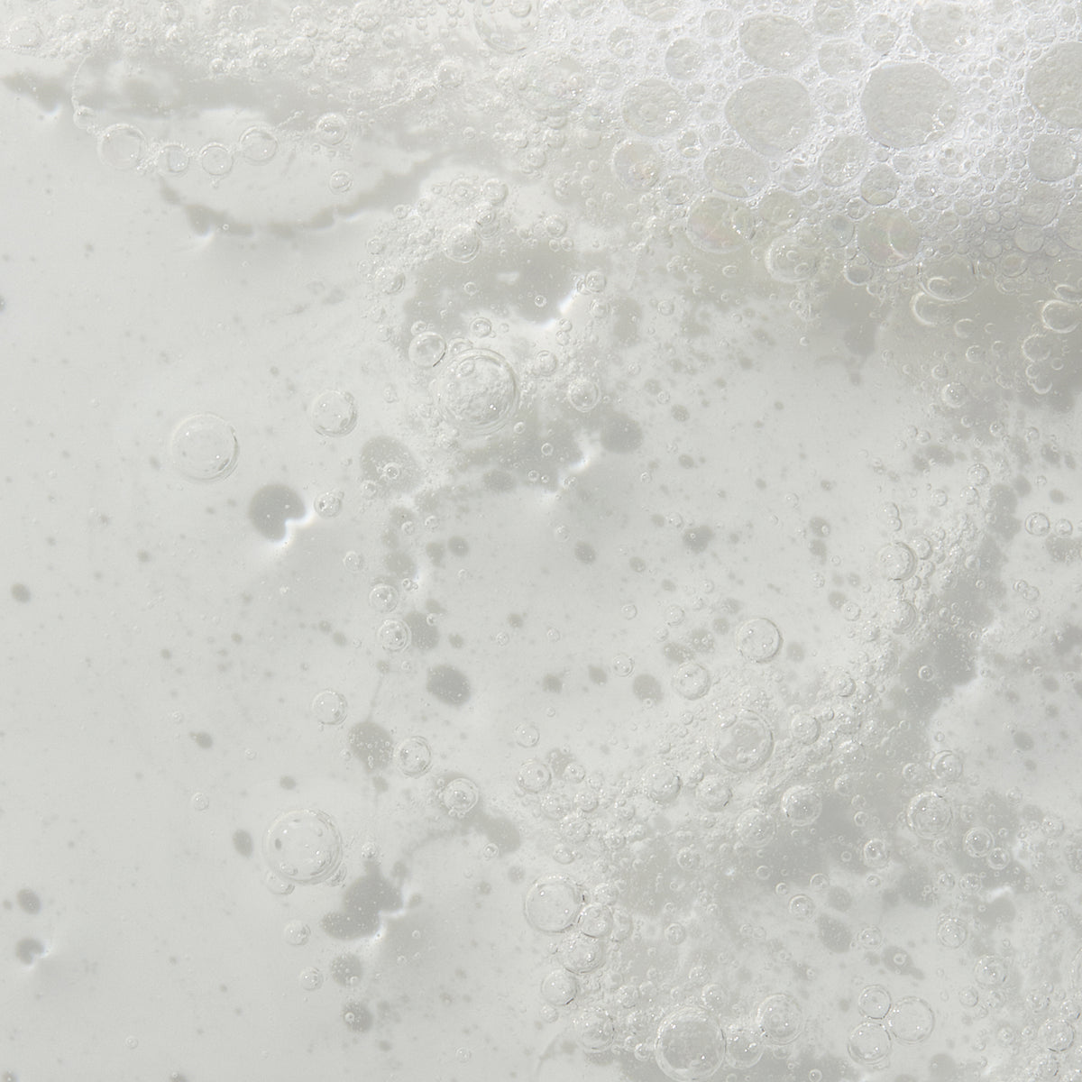 Nahaufnahme einer schaumigen, klaren Reinigungs-Textur mit feinen Bläschen – vermutlich ein schäumender Gesichtsreiniger oder Cleanser.