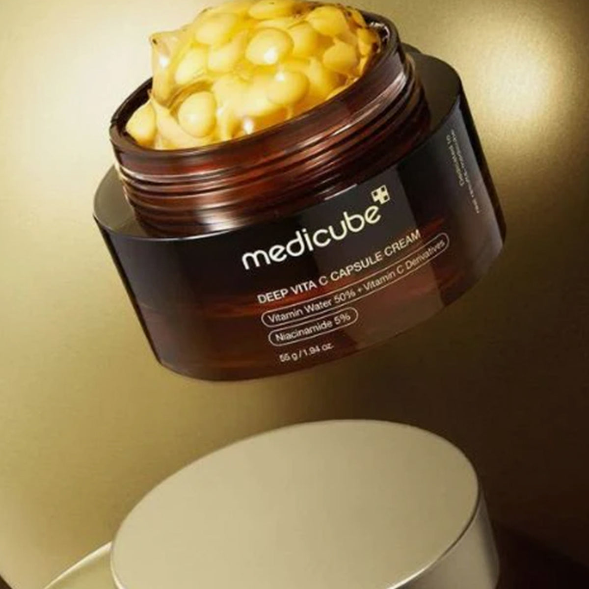 Ein geöffneter Tiegel Deep Vita C Capsule Cream zeigt seine gelben Kapseln vor einem goldenen Hintergrund.