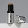 Der silberne Make-up-Stift The Mood Contrast 102 Medium von Mesauda neben silberner Kappe auf grauem Hintergrund.