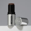 Der silberne Make-up-Stift The Mood Contrast 104 Deep von Mesauda neben silberner Kappe auf grauem Hintergrund.