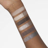 Ein Arm zeigt sechs Swatches der Bare Harmony 2.0 Palette von Mesauda Beauty, die eine Mischung aus schimmernden und matten Lidschattenfarben enthält.