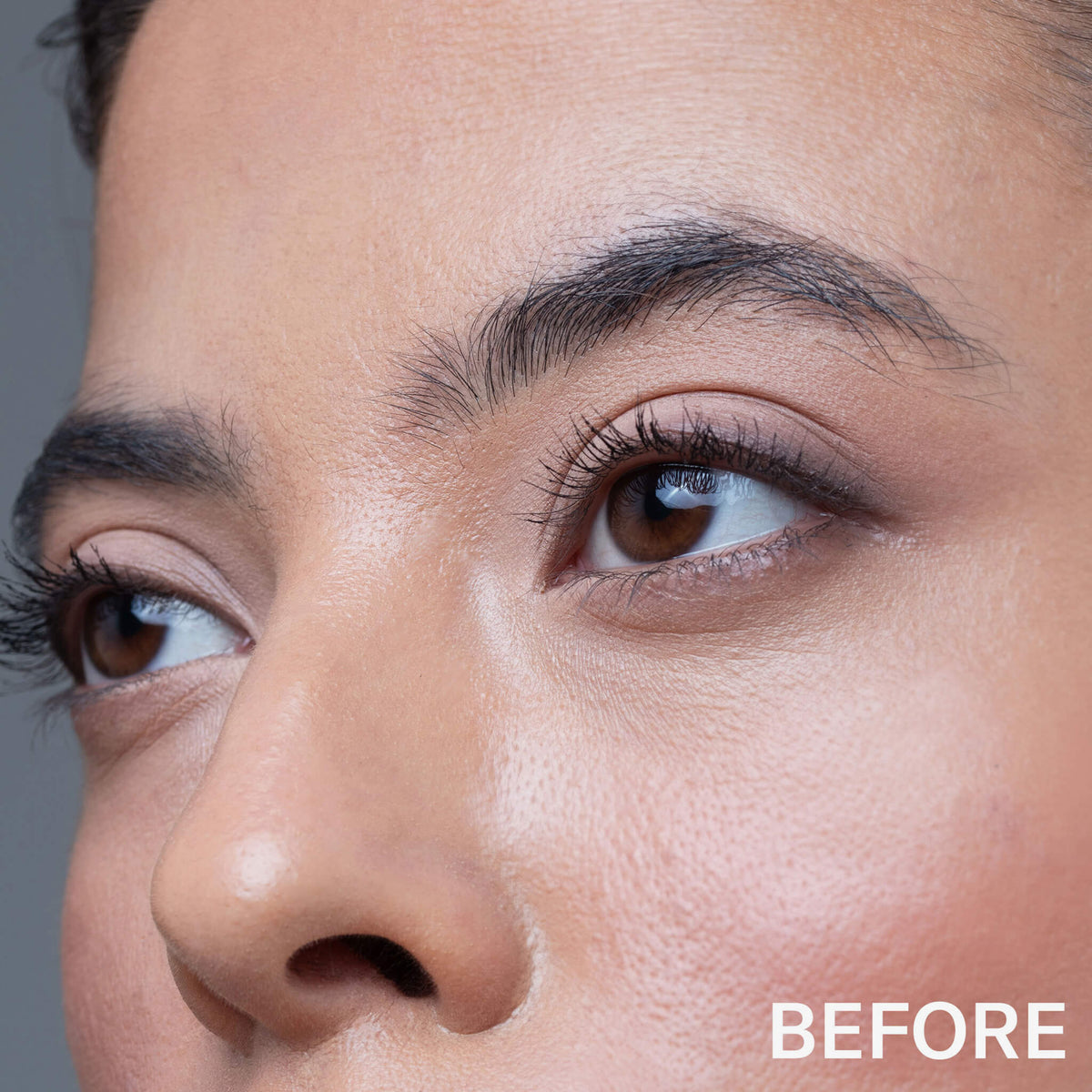 Nahaufnahme des Gesichts einer Person mit natürlicher Haut und Augenbrauen, mit "BEFORE" in der Ecke, das die Brauen vor der Anwendung von Mesauda Beauty Brow a Spell hervorhebt.