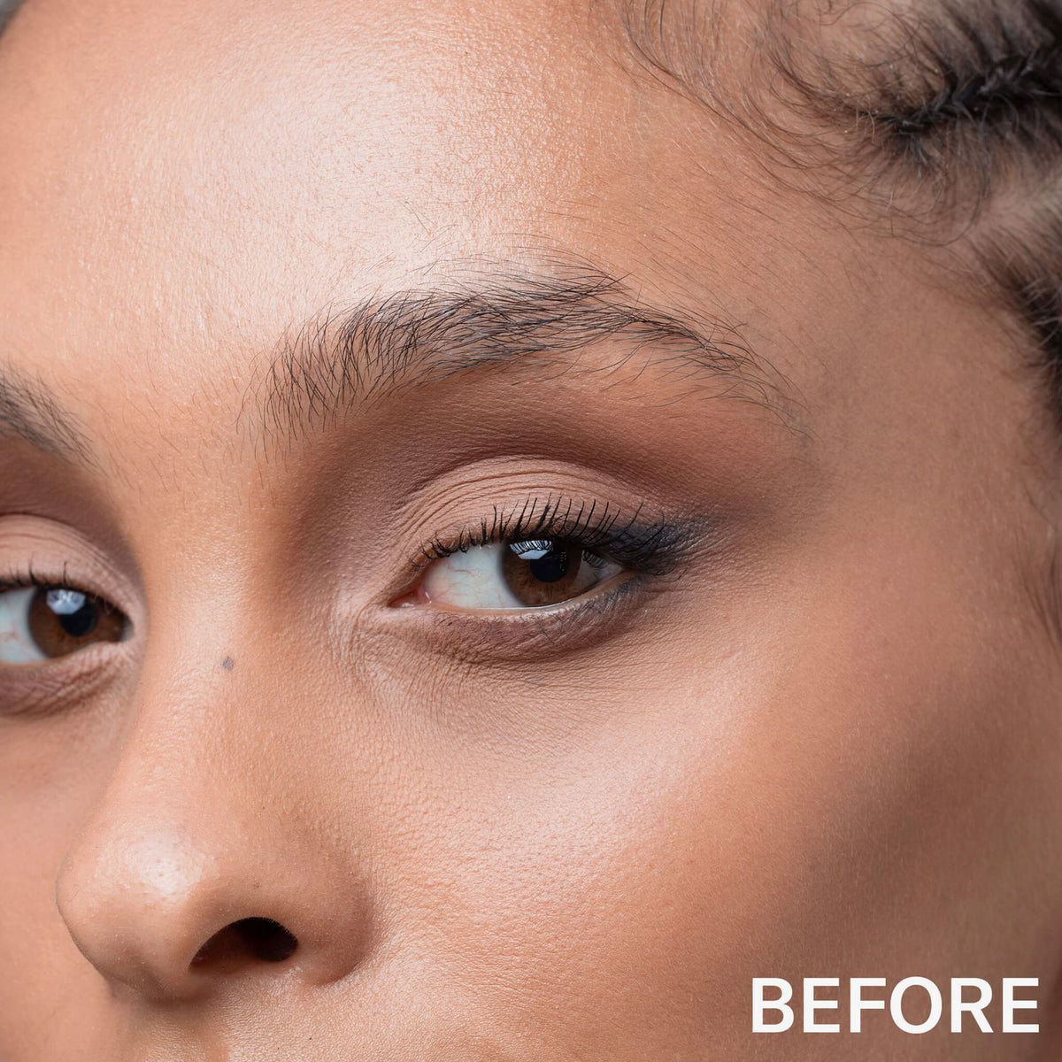 Nahaufnahme eines Frauengesichts mit natürlichem Make-up und sichtbaren Augenbrauen, beschriftet BEFORE, mit dem Brow Glaminate - 101 Clear von Mesauda Beauty.