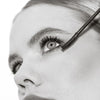 Eine Nahaufnahme zeigt, wie eine Frau die Femuline™ Mascara von Mesauda Beauty mit einer gebogenen Bürste auf ihre oberen Wimpern aufträgt.