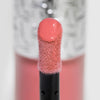 Nahaufnahme des Blushapplikators; darauf ein Tropfen Flush of Blush Peach Delight mit strukturierter silber Kappe im Hintergrund.