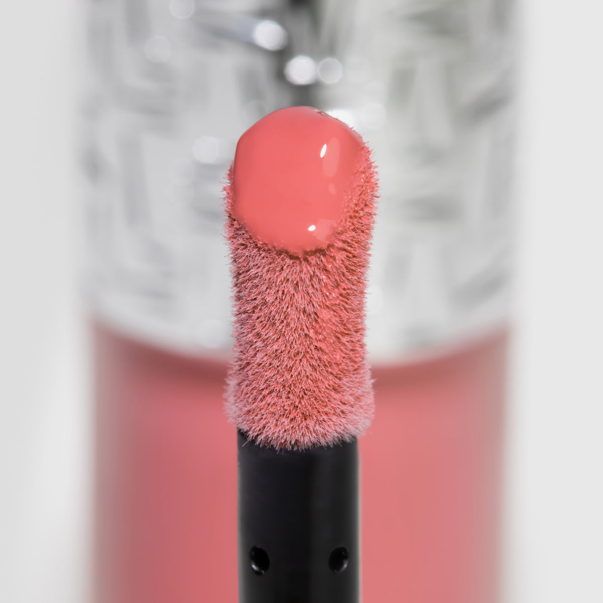 Nahaufnahme des Blushapplikators; darauf ein Tropfen Flush of Blush Peach Delight mit strukturierter silber Kappe im Hintergrund.