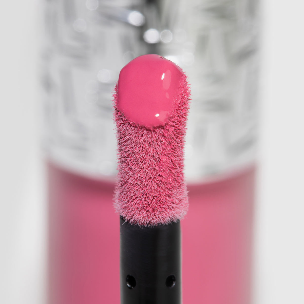 Nahaufnahme des Blushapplikators; darauf ein Tropfen Flush of Blush Petal Pink mit strukturierter silber Kappe im Hintergrund.