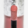 Nahaufnahme des Blushapplikators; darauf ein Tropfen Flush of Blush Soft Mauve mit strukturierter silber Kappe im Hintergrund.