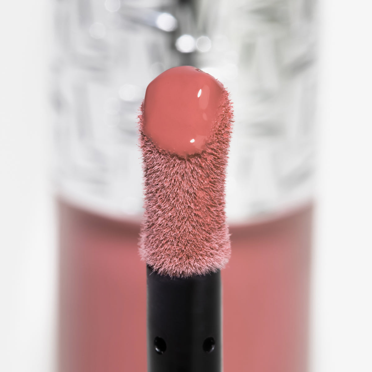 Nahaufnahme des Blushapplikators; darauf ein Tropfen Flush of Blush Soft Mauve mit strukturierter silber Kappe im Hintergrund.