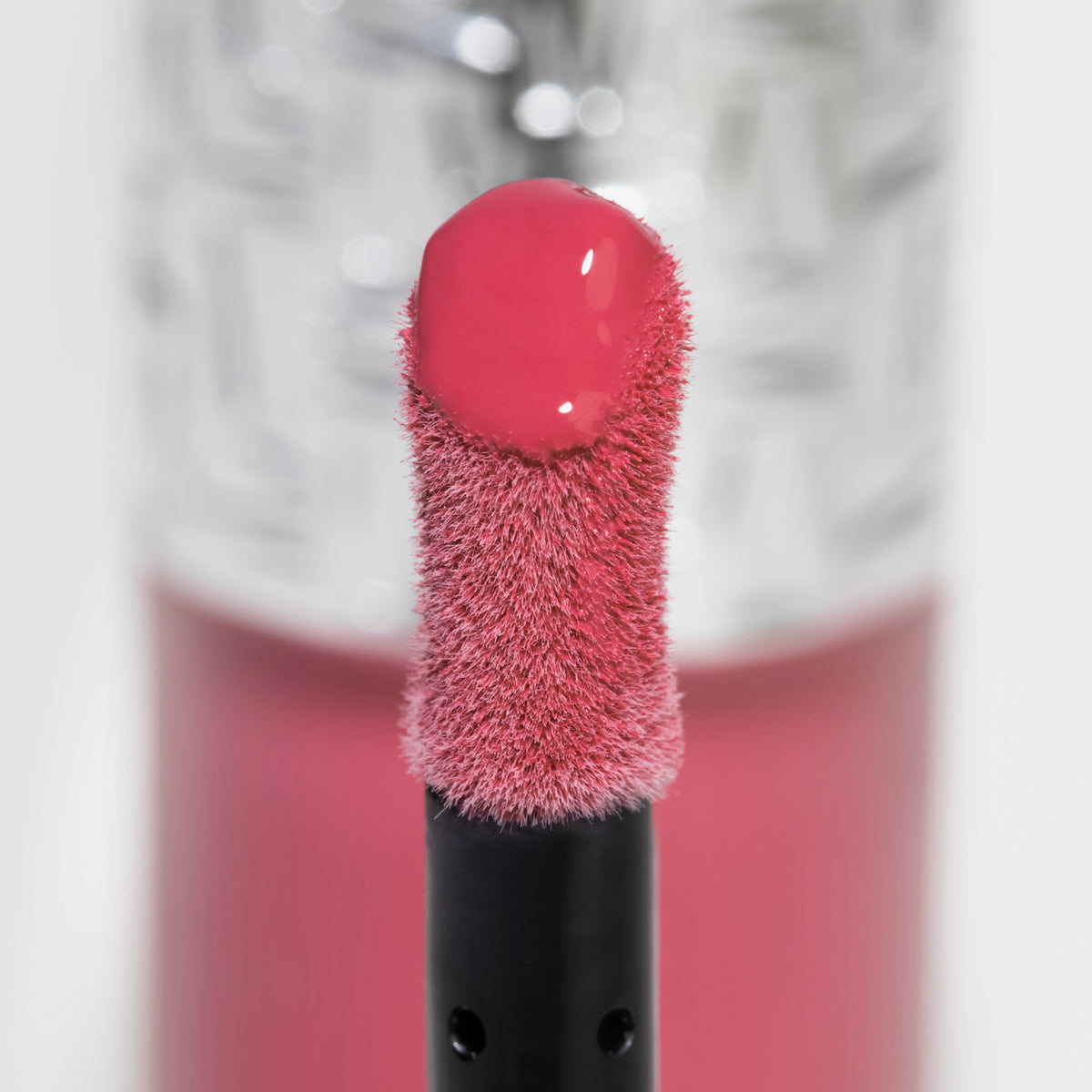 Nahaufnahme des Blushapplikators; darauf ein Tropfen Flush of Blush Strawberry Kiss mit strukturierter silber Kappe im Hintergrund.