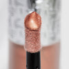 Nahaufnahme des Highlighter-Applikators; darauf ein Tropfen Flush of Light Blossom Shine mit strukturierter silber Kappe im Hintergrund.