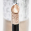 Nahaufnahme des Highlighter-Applikators; darauf ein Tropfen Flush of Light Opal Beam mit strukturierter silber Kappe im Hintergrund.
