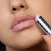 Nahaufnahme einer Person, die Mesauda Beauty Hydramorphosis hellrosa Lippenbalsam auf ihre Lippen aufträgt.
