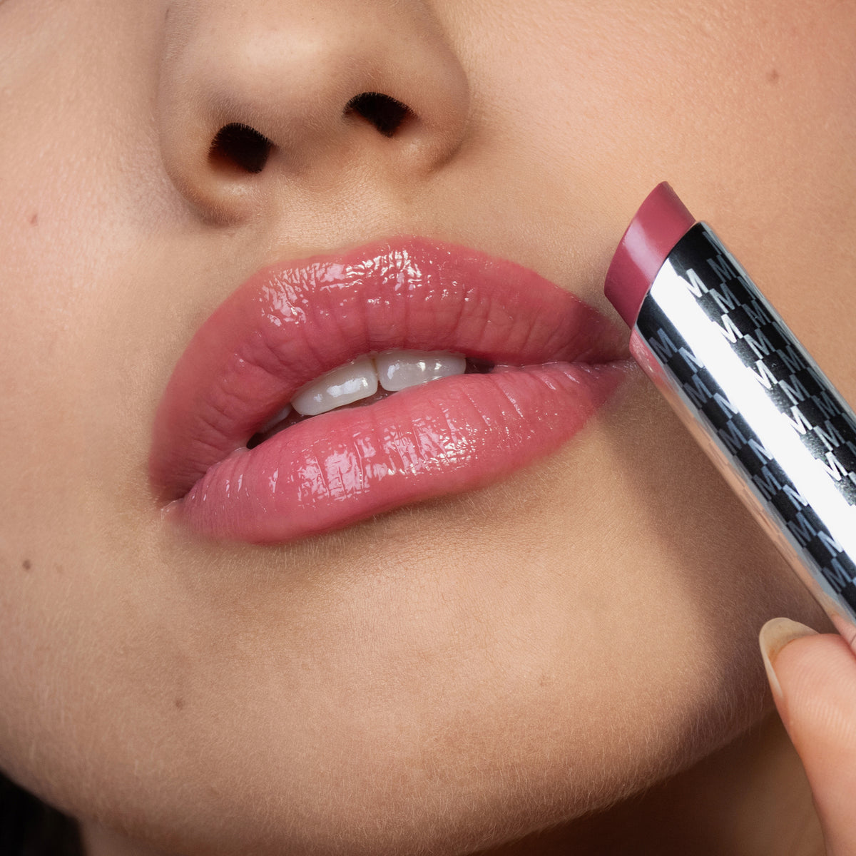 Eine Nahaufnahme einer Person, die den rosafarbenen Lippenstift Hydramorphosis von Mesauda Beauty auf ihre Lippen aufträgt.