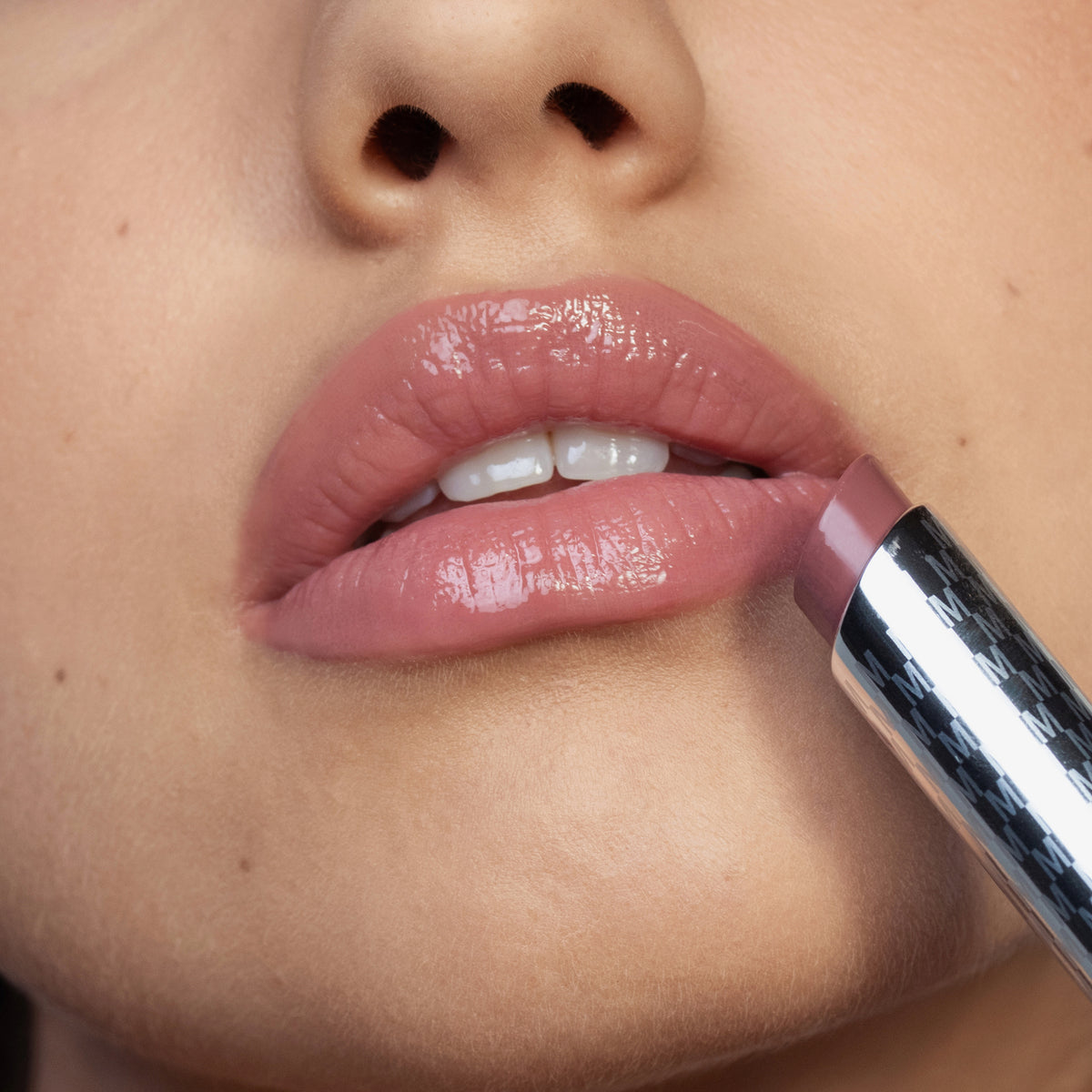 Eine Nahaufnahme zeigt eine Person, die den Hydramorphosis-Lippenstift von Mesauda Beauty auf ihre glänzenden Lippen aufträgt.