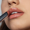Nahaufnahme einer Person, die Hydramorphosis von Mesauda Beauty, einen glänzenden nudefarbenen Lippenstift, auf ihre Lippen aufträgt.