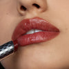 Nahaufnahme einer Person die den Hydramorphosis Lippenstifts von Mesauda Beauty trägt und den Lippenstift an den Mund hält.