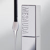 Ein Applikator mit abfließendem Produkt neben einer silbernen Mesauda Beauty LIP PHENOM™ Flasche auf einem hellen Hintergrund.