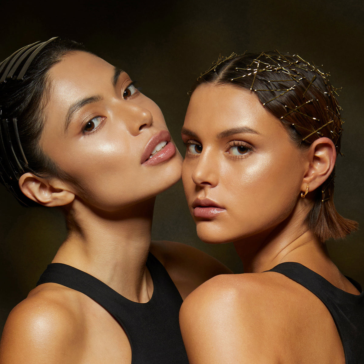 Zwei Frauen mit strahlender Haut posieren eng aneinander in schwarzen Oberteilen, gestylt, und präsentieren Lust For Shine von Mesauda Beauty.