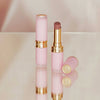 Zwei Beyond Blurry-Lippenstifte in Pink und Gold, einer offen und einer geschlossen, präsentiert auf einer reflektierenden Oberfläche.