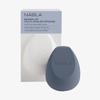 Ein grauer NABLA Cosmetics Blended-up Multi-Angled Sponge neben seiner weiß-grauen Verpackung.