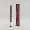 Beerenfarbiger Lidschatten-Stift mit goldener Kappe von NABLA neben der passenden beerenfarbiger Umverpackung mit goldenen Designelementen.