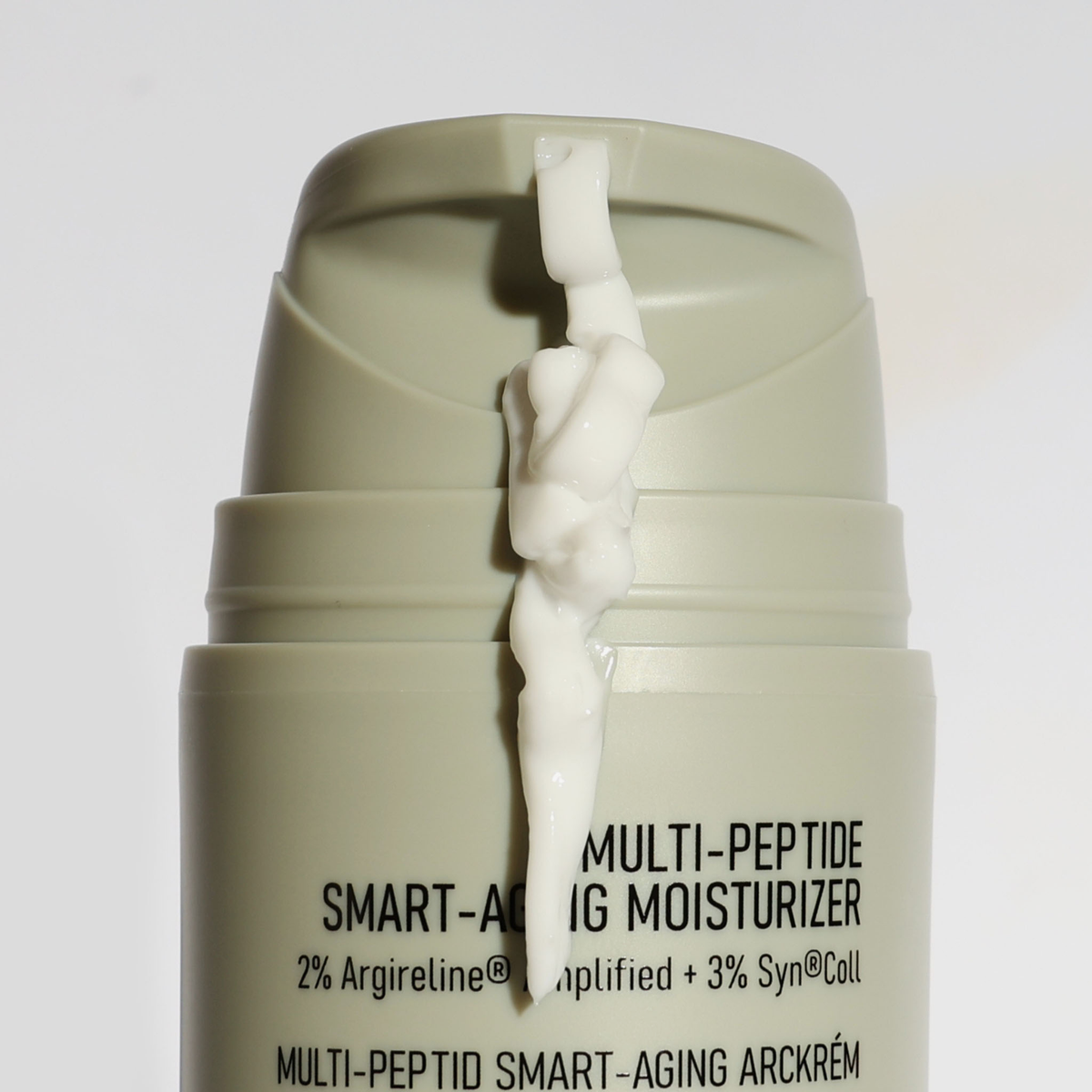 Eine Nahaufnahme der NERDS. Multi-Peptide Smart-Aging Moisturizer zeigt, wie die weiße Creme aus der beigen Pumpflasche austritt.