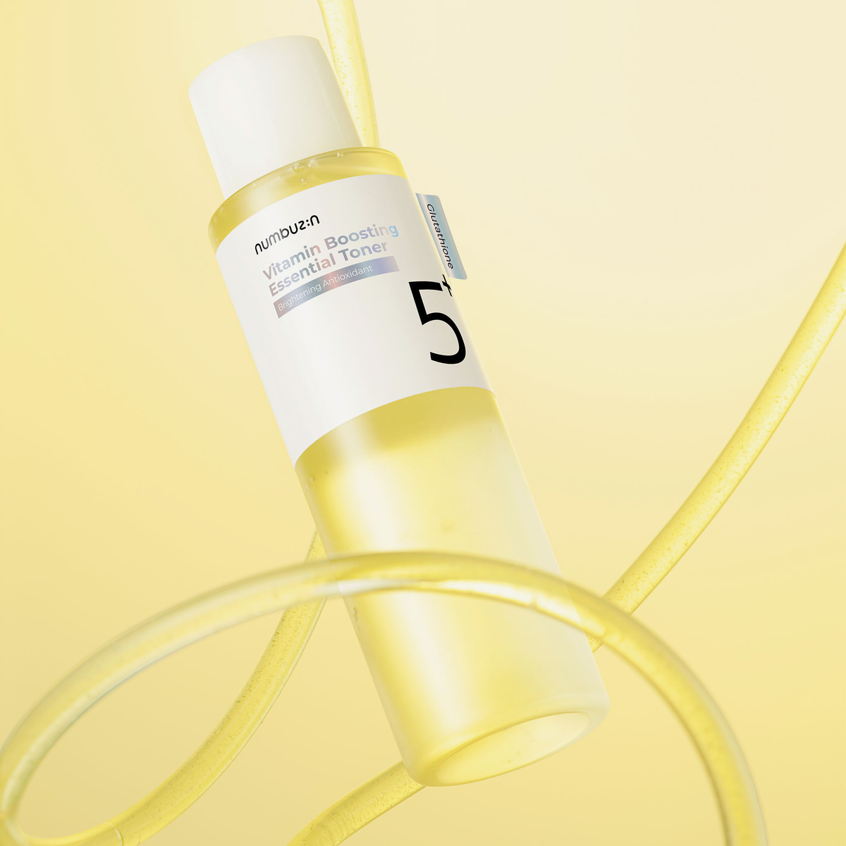 Eine 200-ml-Flasche „Numbuzin No. 5+ Vitamin Boosting Essence Toner“ mit gelber Flüssigkeit vor gelbem Hintergrund.