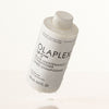 Schwebende nasse Flasche OLAPLEX N°5 FINE Bond Maintenance Conditioner vor weißem Hintergrund.