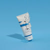 Eine Tube Birch Juice Moisturizing Cleanser, aus der klares Gel herausfließt, vor einem einfarbig blauen Hintergrund.