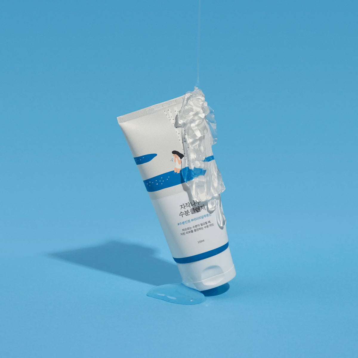 Eine Tube Birch Juice Moisturizing Cleanser, aus der klares Gel herausfließt, vor einem einfarbig blauen Hintergrund.