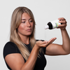 Eine Frau gießt Bio-Pilixin® Shampoo+Women von Scandinavian Biolabs in ihre Handfläche vor einem schlichten weißen Hintergrund.