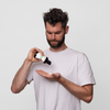 Ein Mann in einem weißen T-Shirt gießt Scandinavian Biolabs Bio-Pilixin® Conditioner+ Men aus einer Flasche in seine Hand vor einem schlichten weißen Hintergrund.
