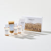 Das Madagascar Centella Travel Kit mit fünf Hautpflegeprodukten und einer Schachtel wird auf einer weißen Oberfläche präsentiert.