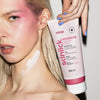 Frau mit rosa Make-up hält eine Tube Rouge365 Essential Cream; die Creme ist auch auf ihrem Hals aufgetragen.