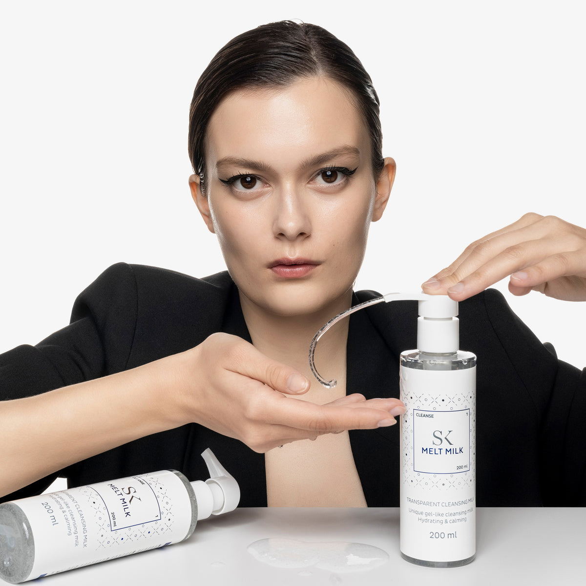 Frau drückt klares Gel aus einer Pumpflasche auf ihre Hand und blickt dabei in die Kamera.