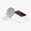 Der Flip n Charge Power Bank Compact LED Mirror mit weißem Kabel liegt neben einem lila Smartphone auf weißem Hintergrund.