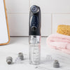 Der HYDRO EXFOLIATOR stehen neben einem Schwamm und Handtüchern auf der Badezimmerablage.