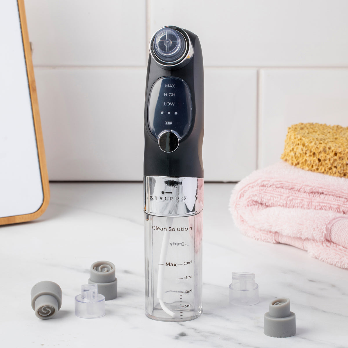 Der HYDRO EXFOLIATOR stehen neben einem Schwamm und Handtüchern auf der Badezimmerablage.