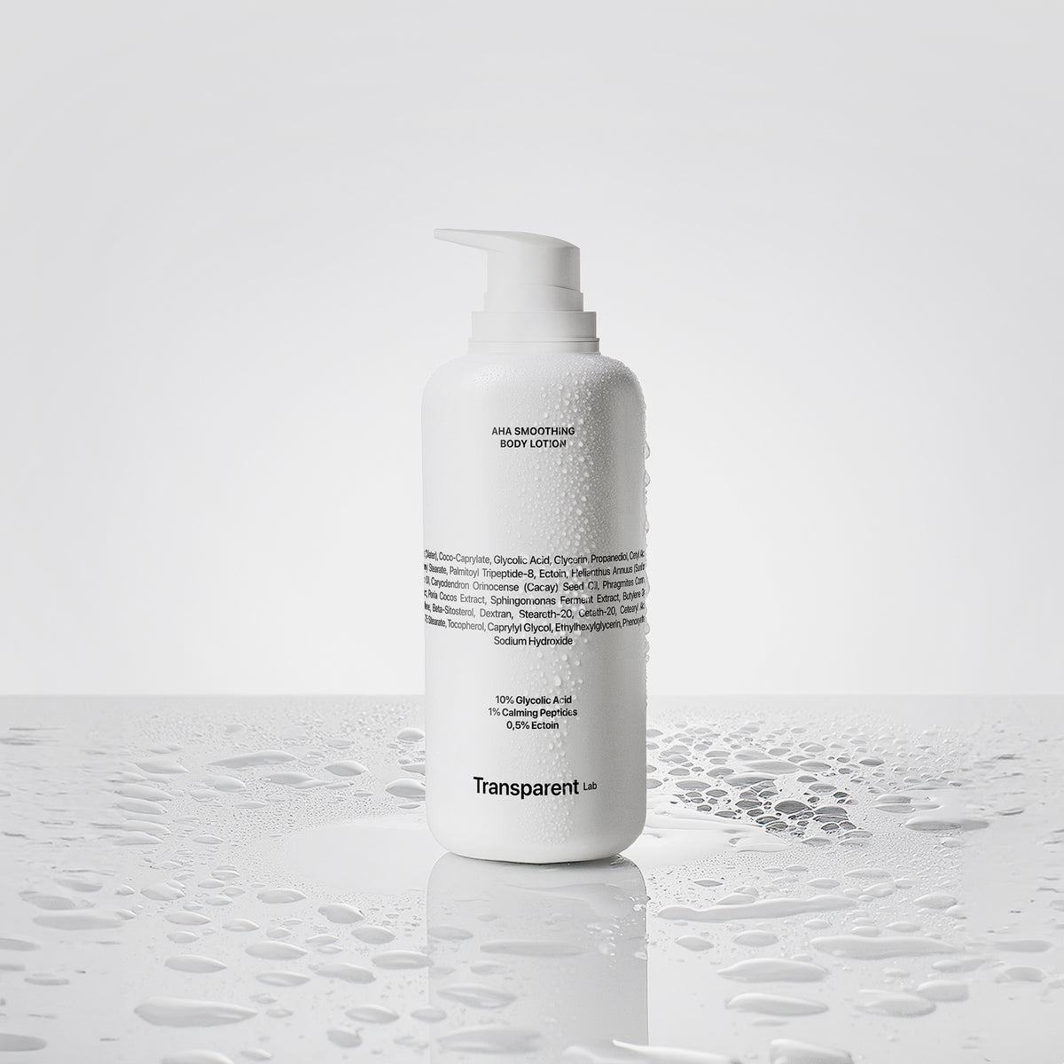 Eine Flasche AHA Smoothing Body Lotion steht mit Wassertropfen auf einer nassen Oberfläche.